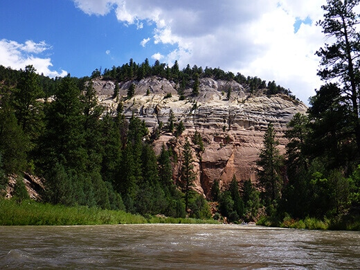 Kayak Camping on the Rio Chama Canyon walls striped in vivid shades of vermillion, pink, yellow, and white