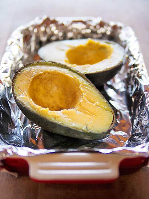 Place avocado halves in a baking dish lined with foil