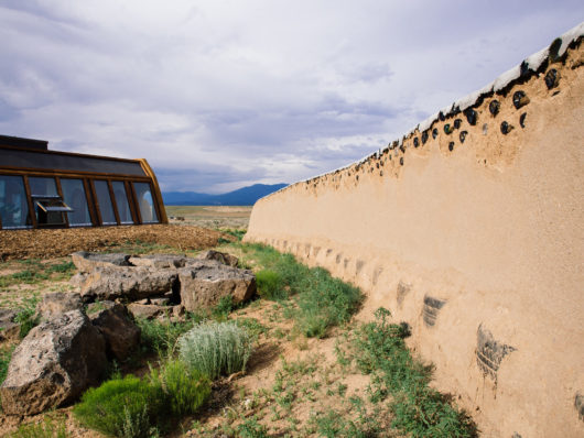 Upcycled wall made from tires, cans, and bottles plastered with adobe mud