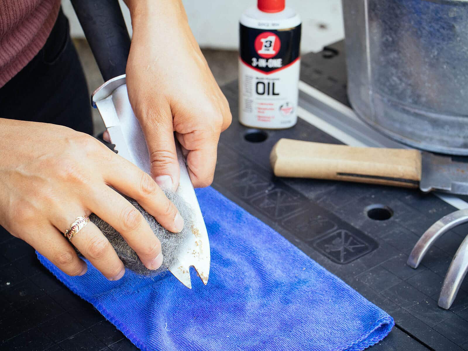 Hand scrubbing rust off a hori hori knife with steel wool