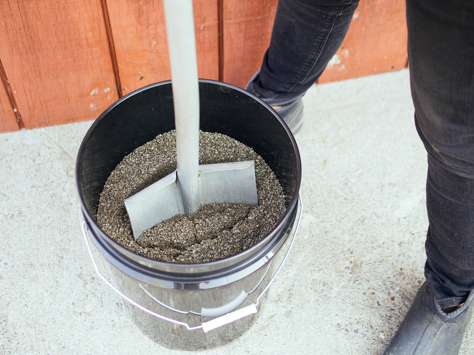 Shovel inserted into a 5-gallon bucket filled with oily sand