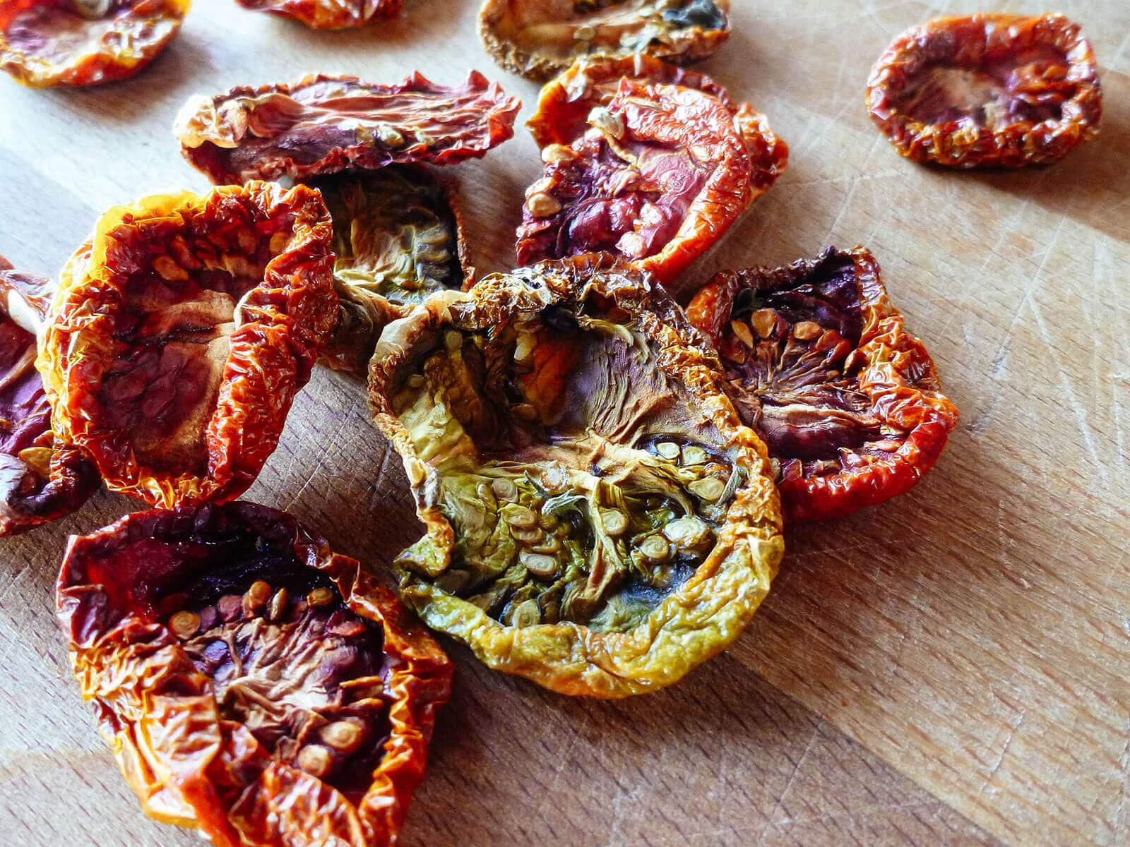 Colorful oven-dried heirloom tomatoes scattered across a butcher block