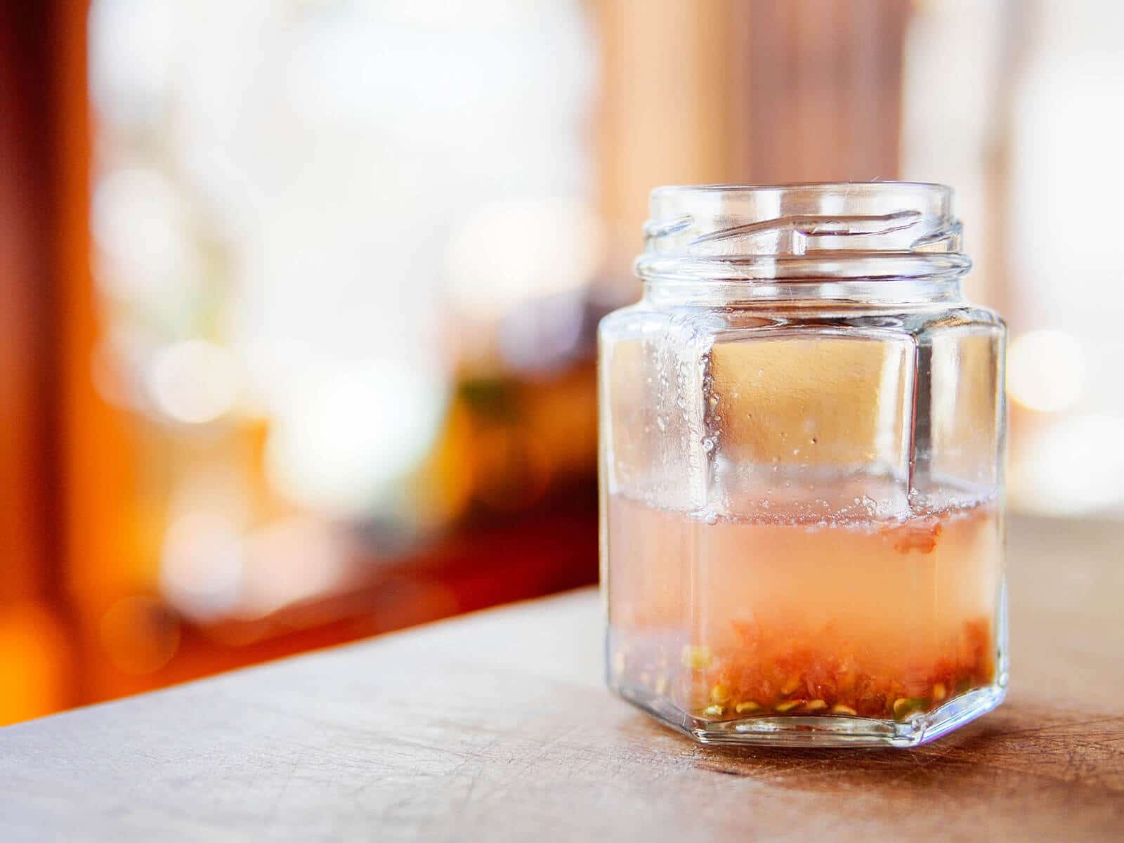 Side view of tomato seeds covered with water in a jar