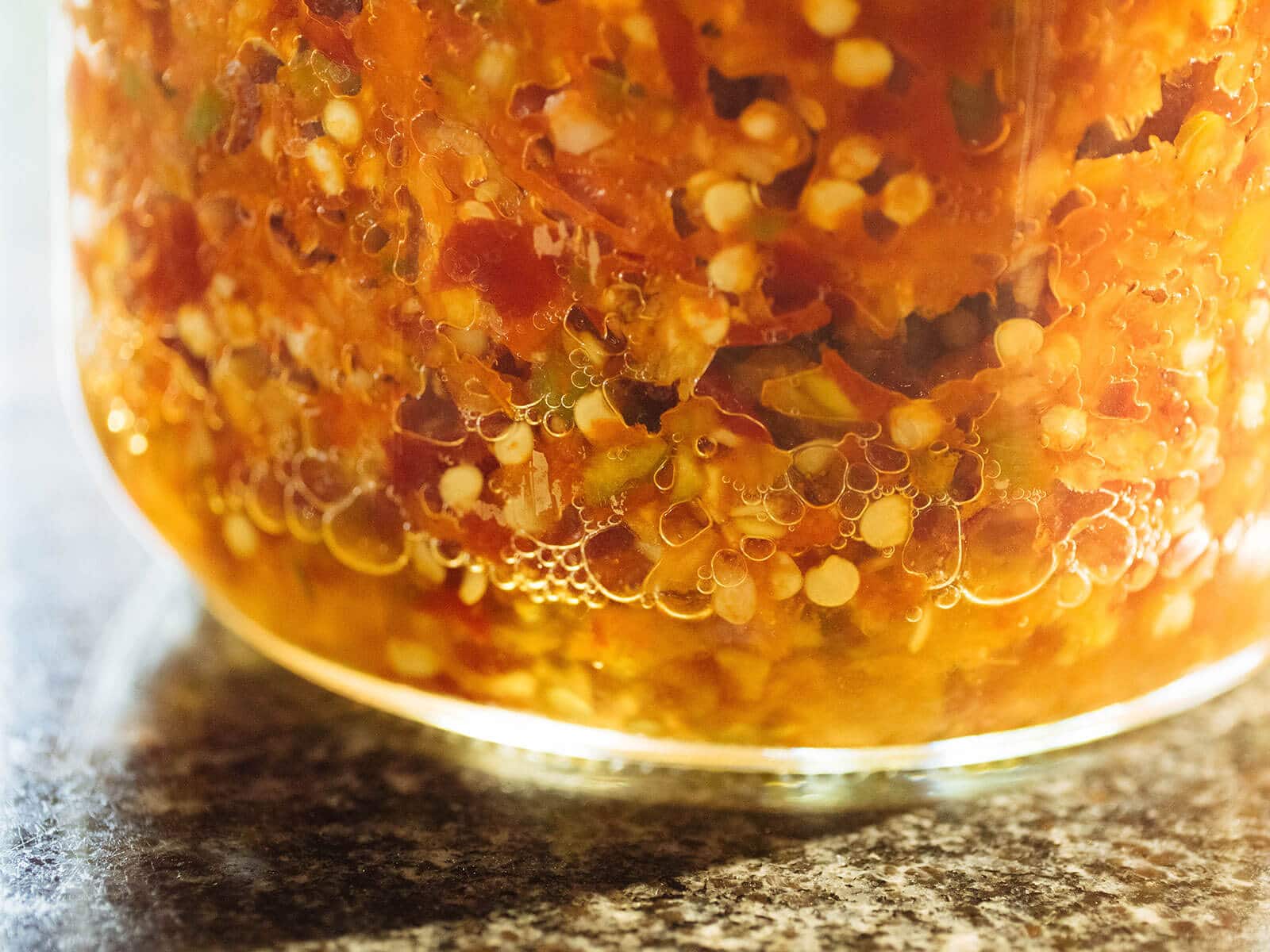 Close-up of lactic acid bacteria bubbles in an actively fermenting jar of chile peppers
