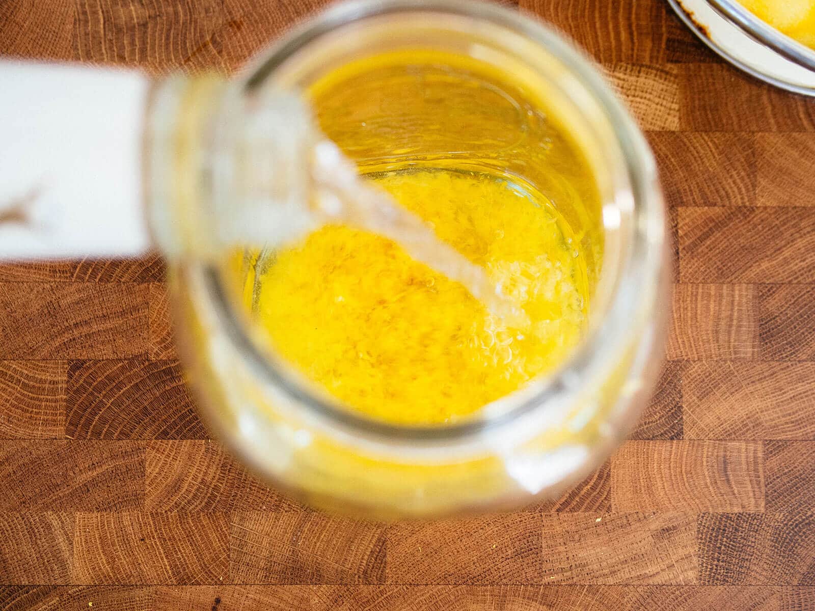 Everclear grain alcohol being poured over lemon zest in a jar