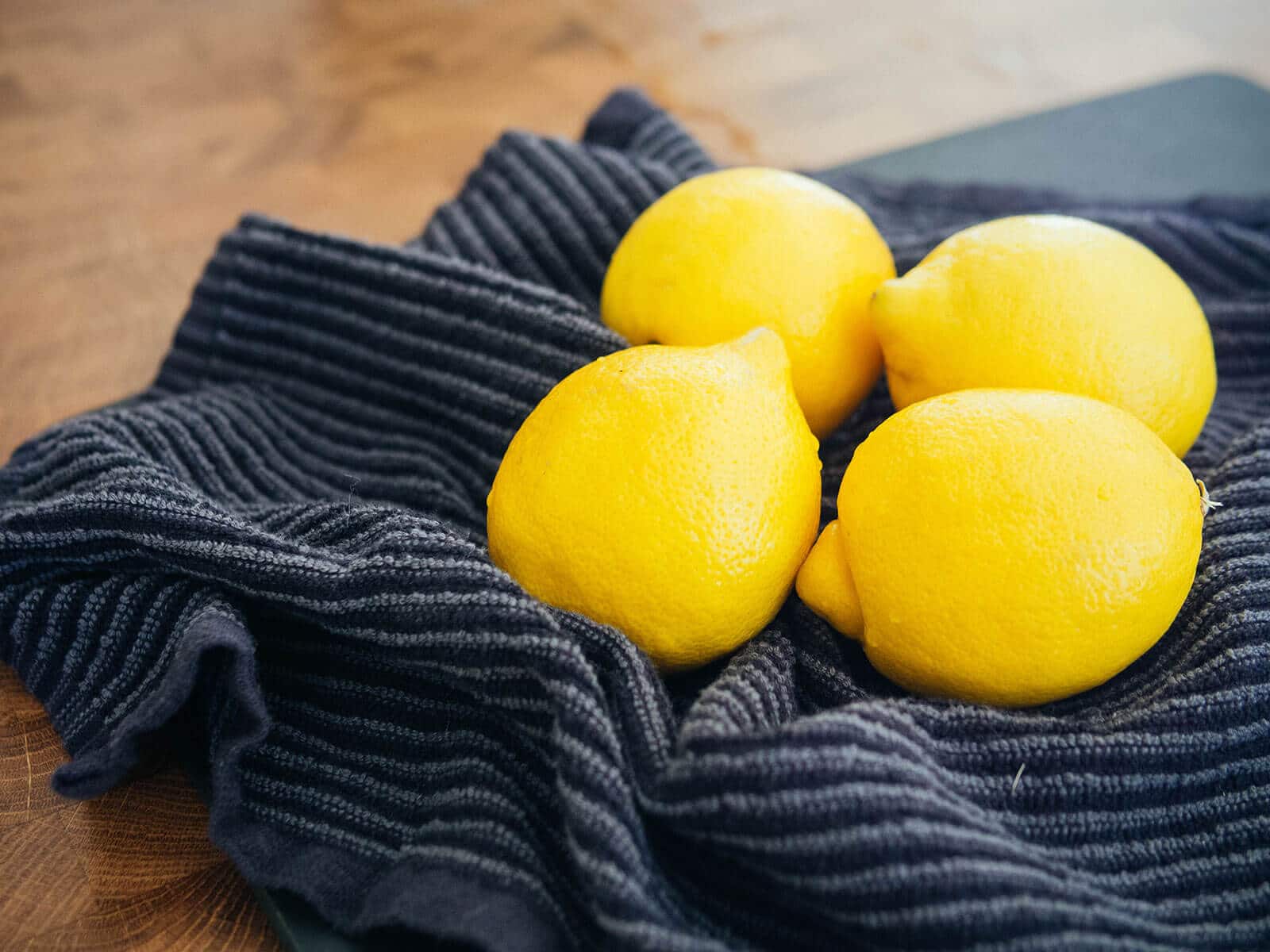 Four lemons washed and drying on a kitchen towel