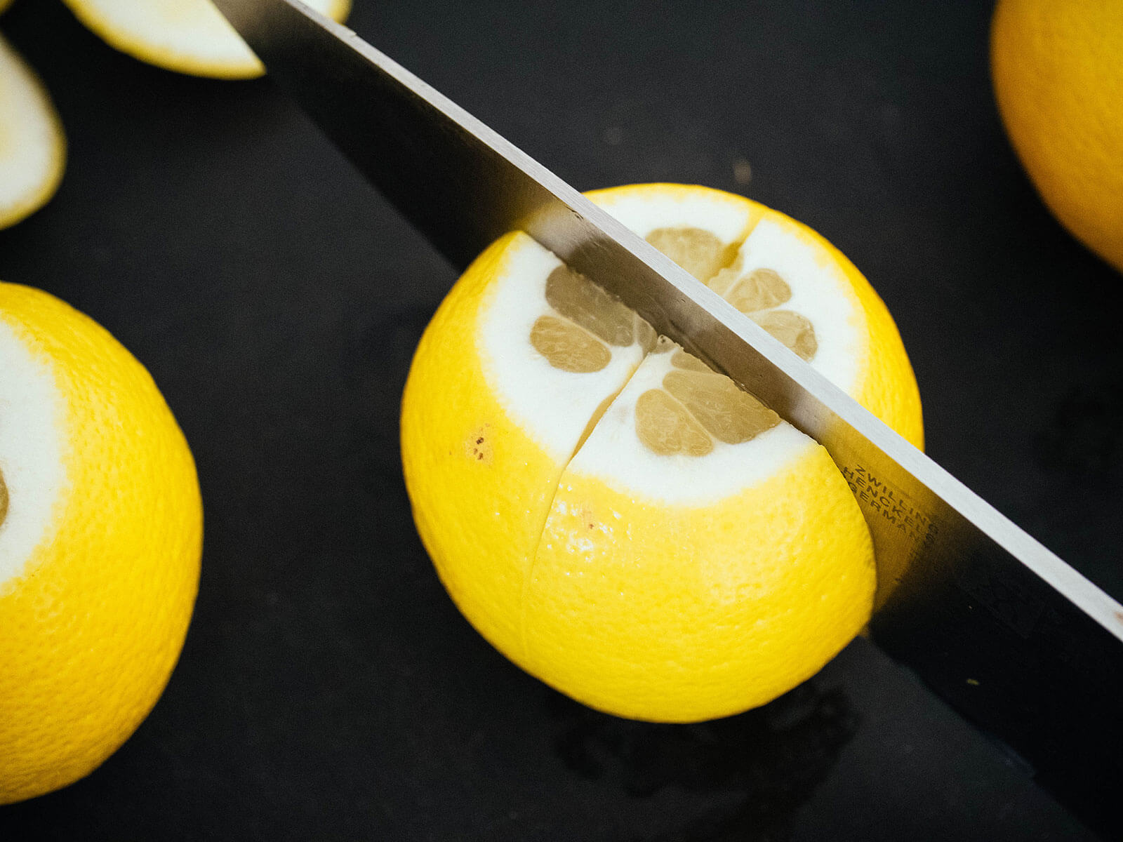 A knife slicing a lemon into quarters