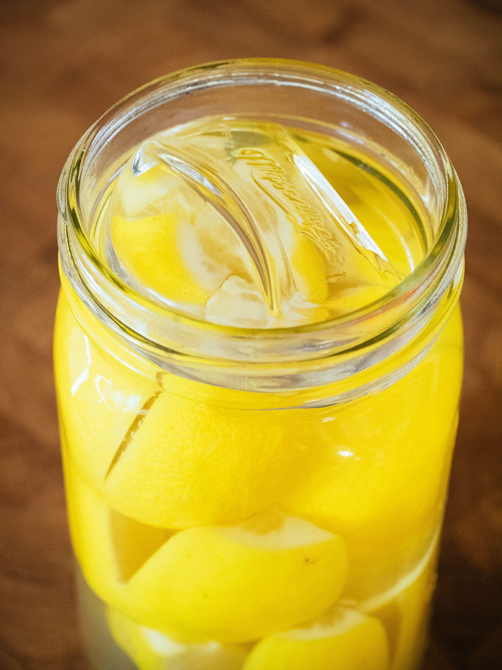 Mason jar full of salted lemons with a glass fermenting weight holding them down