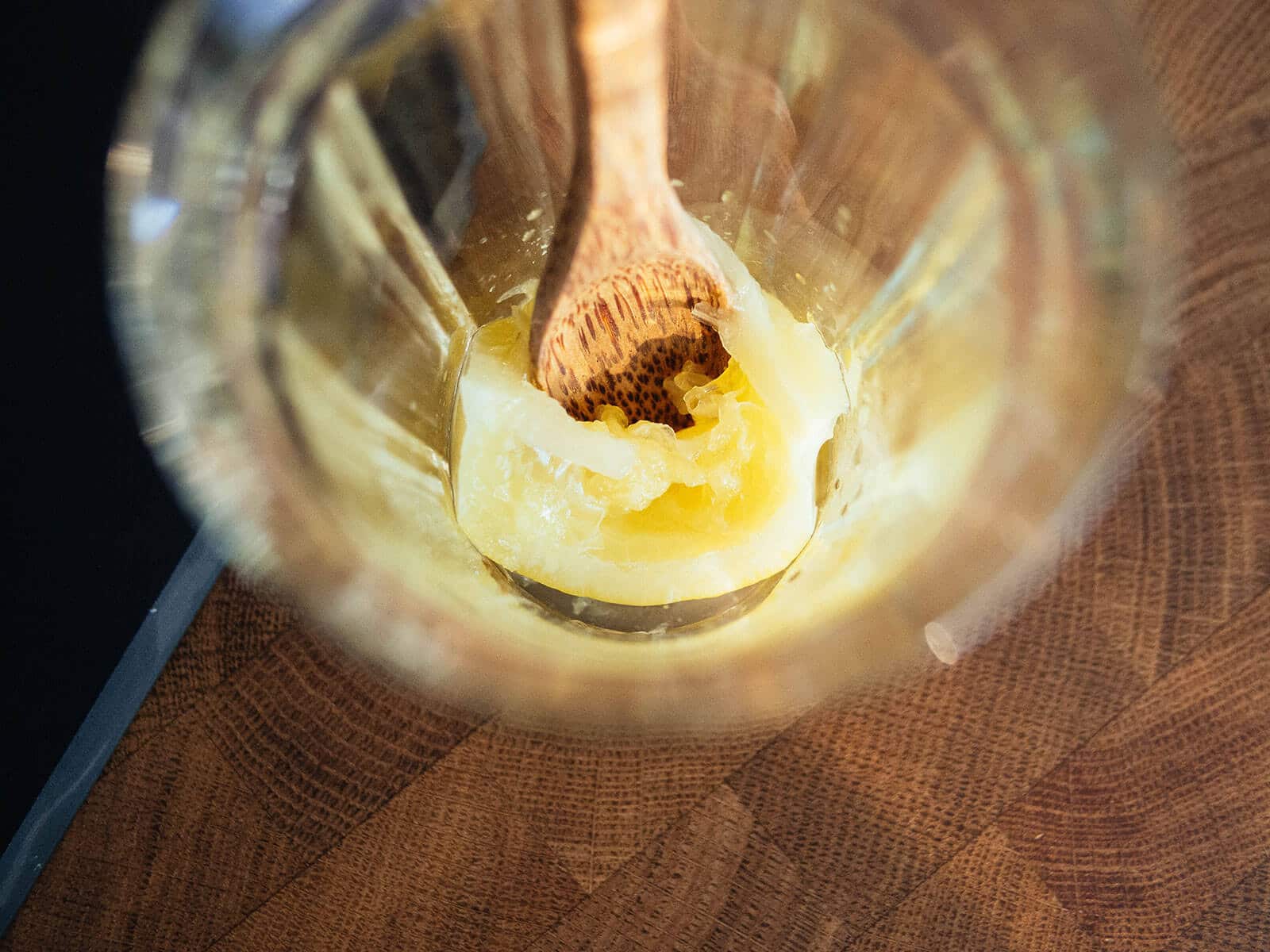 Wooden spoon muddling a Vietnamese preserved lemon in a glass