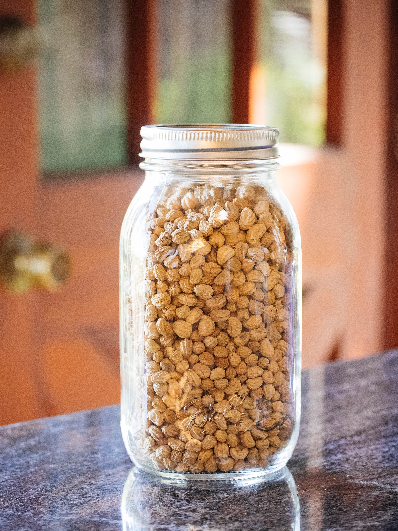 A glass jar on a counter filled with nasturtium seeds