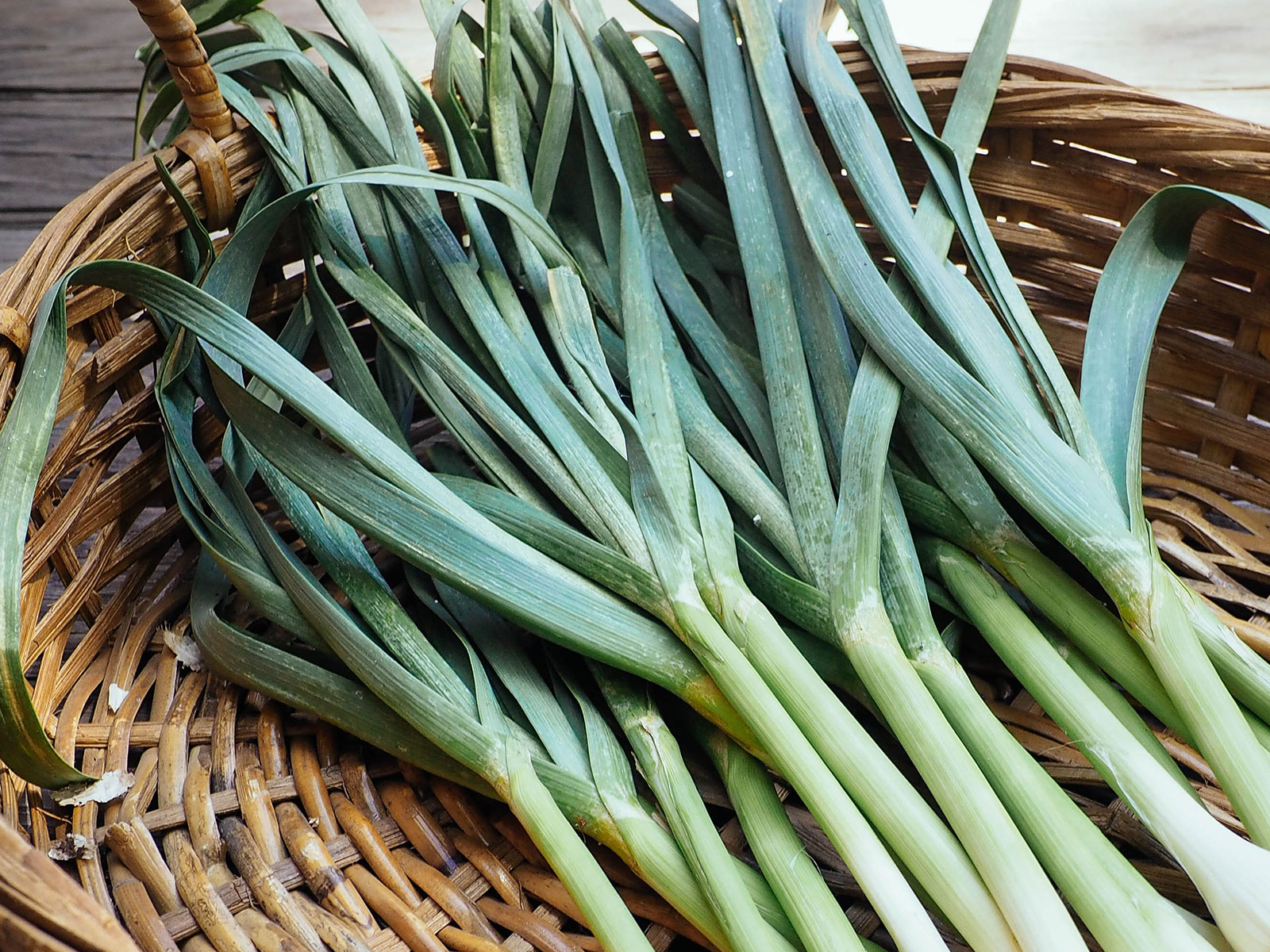 Pile of garlic greens in a wicker basket